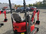 a red mini excavator parked in a parking lot with other vehicles in the background