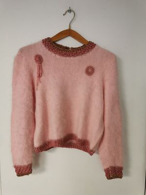 un pull rose suspendu à un cintre accroché au mur devant une porte