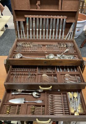 beaucoup d'argenterie dans un coffret en bois posé sur une table