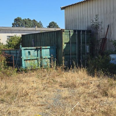 a green container sitting in a field next to a building