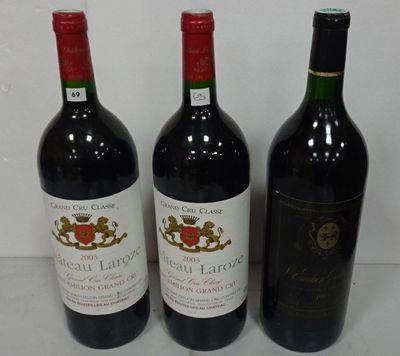 three bottles of red wine are lined up on a table