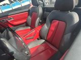 l'intérieur d'une voiture de sport rouge et noire, équipée de sièges en cuir noir