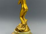 une statue en or représentant une femme, posée sur un socle en marbre