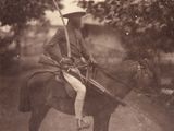 an old photo of a man on a horse with a rifle