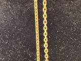 an image of a gold cross necklace on a black surface