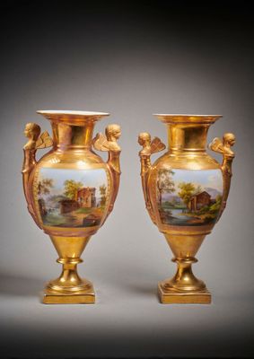deux vases en or ornés de peintures, posés sur une table