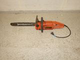 an orange chainsaw sitting on the floor next to a white wall