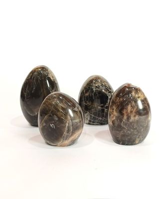 quatre œufs en marbre noir posés sur une surface blanche