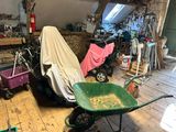 a green wheelbarrow in a garage with a cover over it
