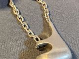 a silver necklace that has a silver bell on it