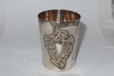 a silver cup sitting on a table with a silver handle