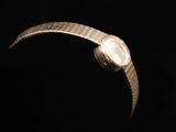 a close up of a watch on a black surface with a black background