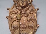 une plaque en or sur laquelle sont gravés un visage et une épée
