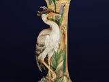 a close up of a vase with a bird on top of it