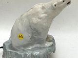 a ceramic polar bear sitting on a rock on a white background