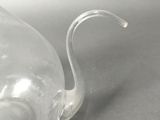 a clear glass swan shaped teapot on a table