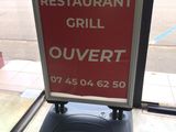 a sign that says restaurant grill ouvertt on the sidewalk