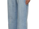 a woman in a white shirt and blue jeans stands with her back to the camera