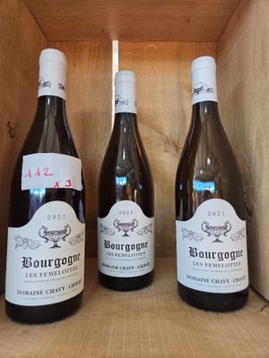 trois bouteilles de vin sont posées dans une caisse en bois sur une étagère