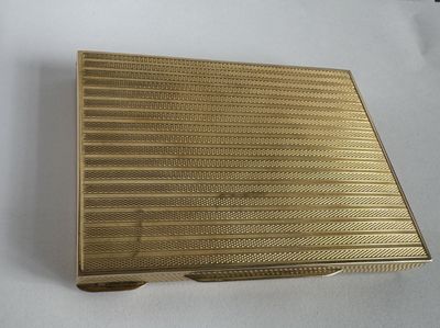 an image of a gold cigarette case sitting on top of a white table