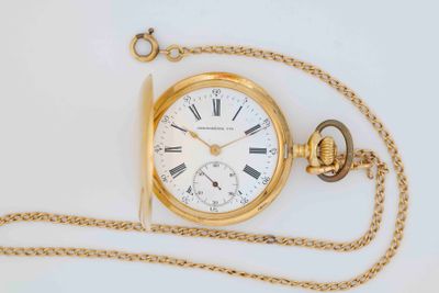 a gold pocket watch with a chain on a white surface