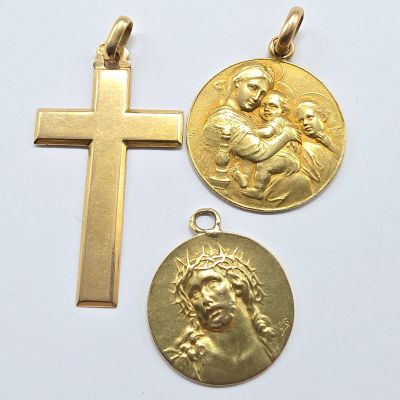 three gold religious pendants with a cross on a white background
