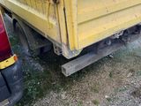 a yellow dump truck that is parked next to a red truck