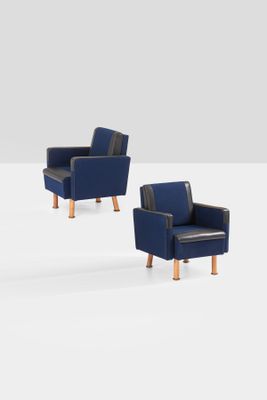two blue chairs sitting next to each other on a white surface