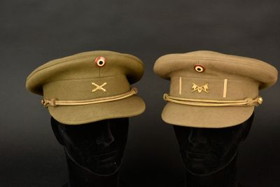une paire de casquettes militaires posées sur des têtes de mannequins, sur fond noir