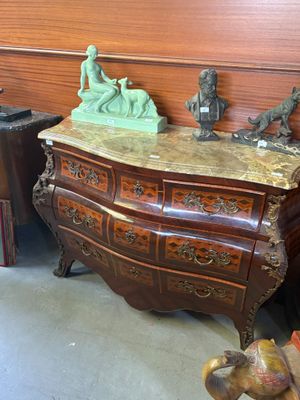 une commode surmontée de statues, dans une pièce