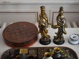 two figurines sitting on a tray next to a tray with other items