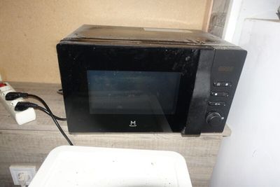 un four à micro-ondes noir posé sur un plan de travail à côté des toilettes