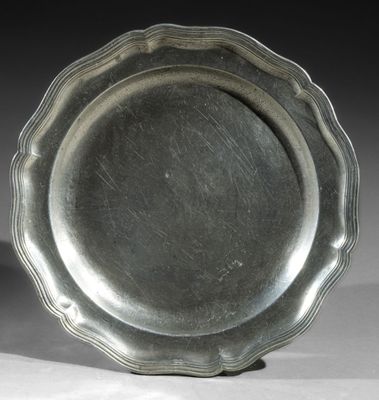 silver plate with scalloped edge on stand on white surface