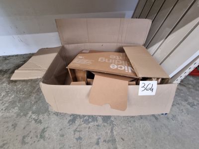 une boîte en carton sur laquelle est posée une pancarte, posée par terre