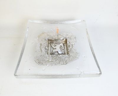 a small glass plate with a lit candle in it