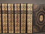 six books in black and gold covers sitting on top of each other