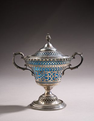 an ornate silver and blue vase with handles on a white surface