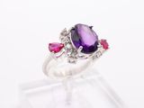 a close up of a ring with a purple stone surrounded by pink stones