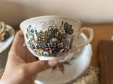 a person holding a cup and saucer on a table