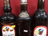 Plusieurs bouteilles d'alcool sont alignées sur un support rouge