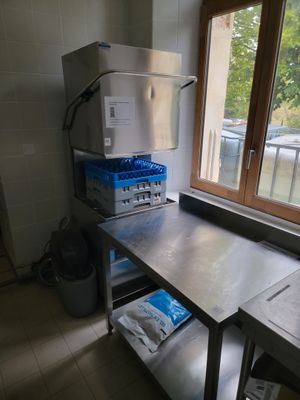 une cuisine équipée d'une table en inox et d'un réfrigérateur