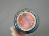a person holding a blue and pink vase in their hand