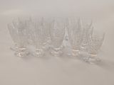 six clear glass goblets lined up on a white surface