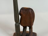 a wooden elephant with a pipe next to it on a white surface