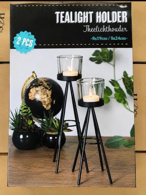 two tealight holders with candles on them on a table