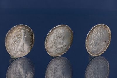 trois pièces d'argent empilées les unes sur les autres sur une surface bleue