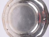 a silver plate on a white surface with a red stripe