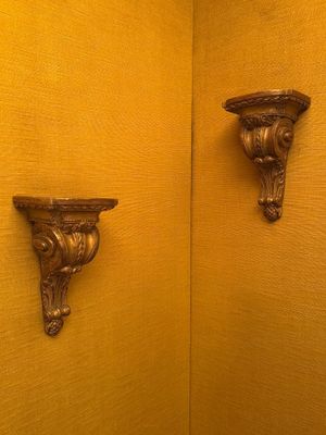des murs jaunes dans une salle de bains, avec deux supports décorés fixés au mur