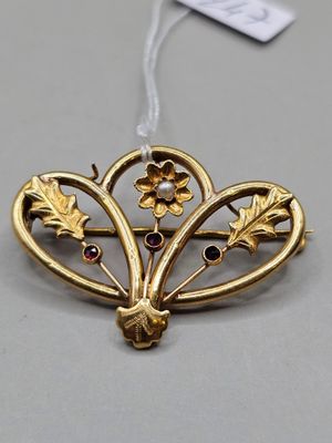 a close up of a gold brooch with flowers and leaves