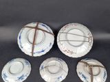 four porcelain plates with blue and white designs on them on a black surface